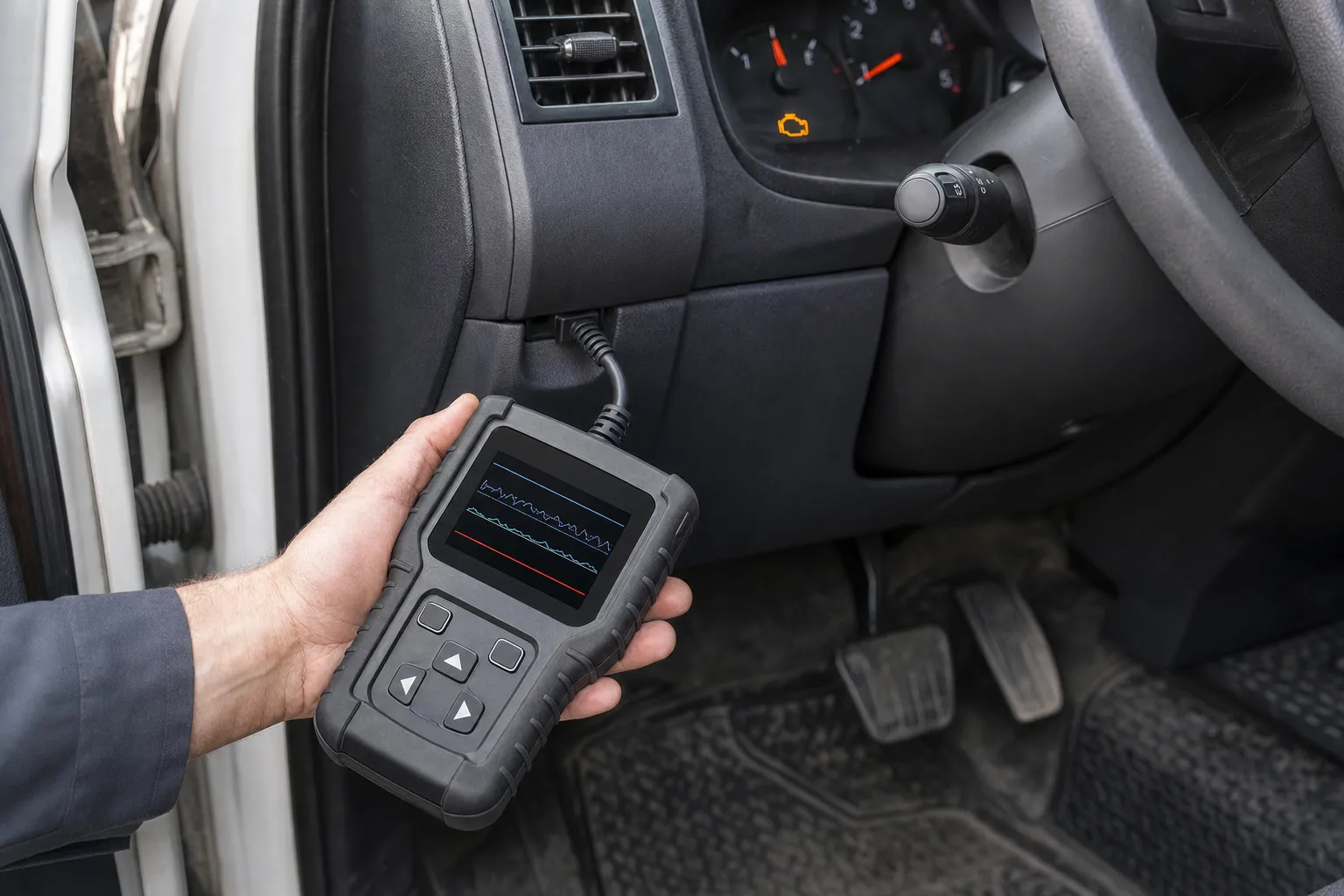 Diagnostic scan tool connected under the dashboard of a work truck